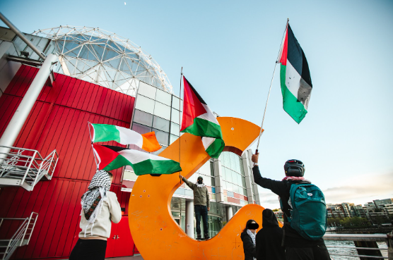 a group of people holding Palestinian flags outside of Science World