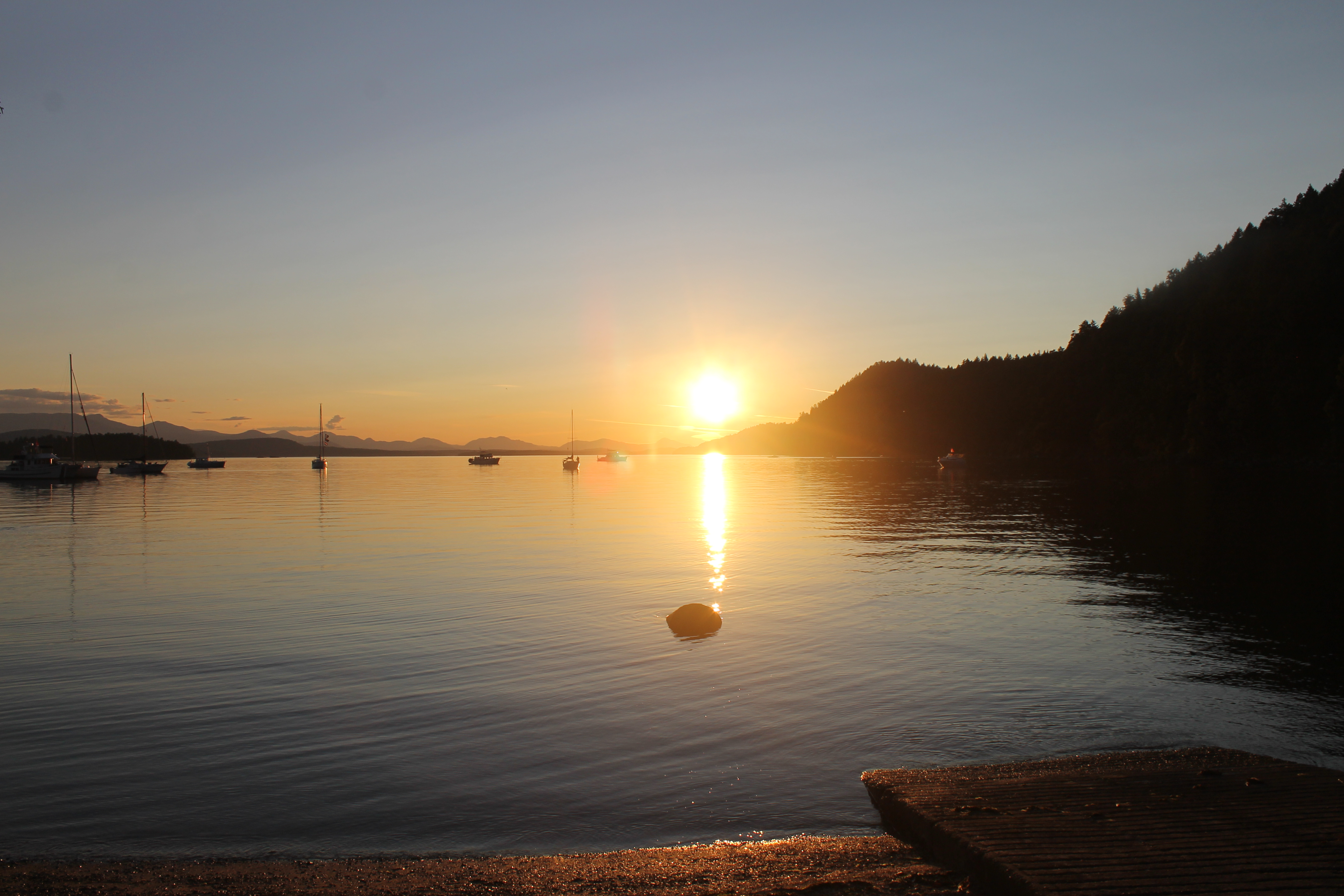 the sun setting over a body of water with boats