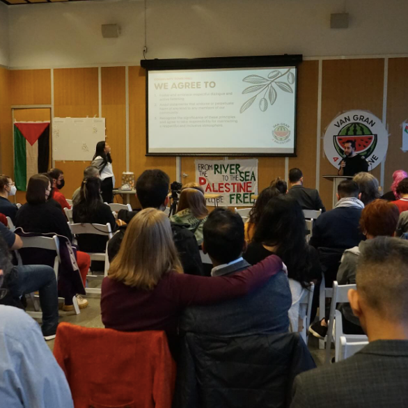 a photo from the town hall showing a crowd of people sitting in chairs and a speaker at a podium