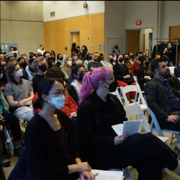 a room full of people sitting in chairs listening to a speaker at the town hall event