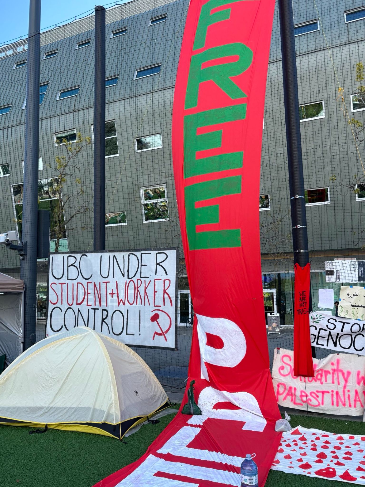 a tent and a banner that says Free Palestine in front of a building