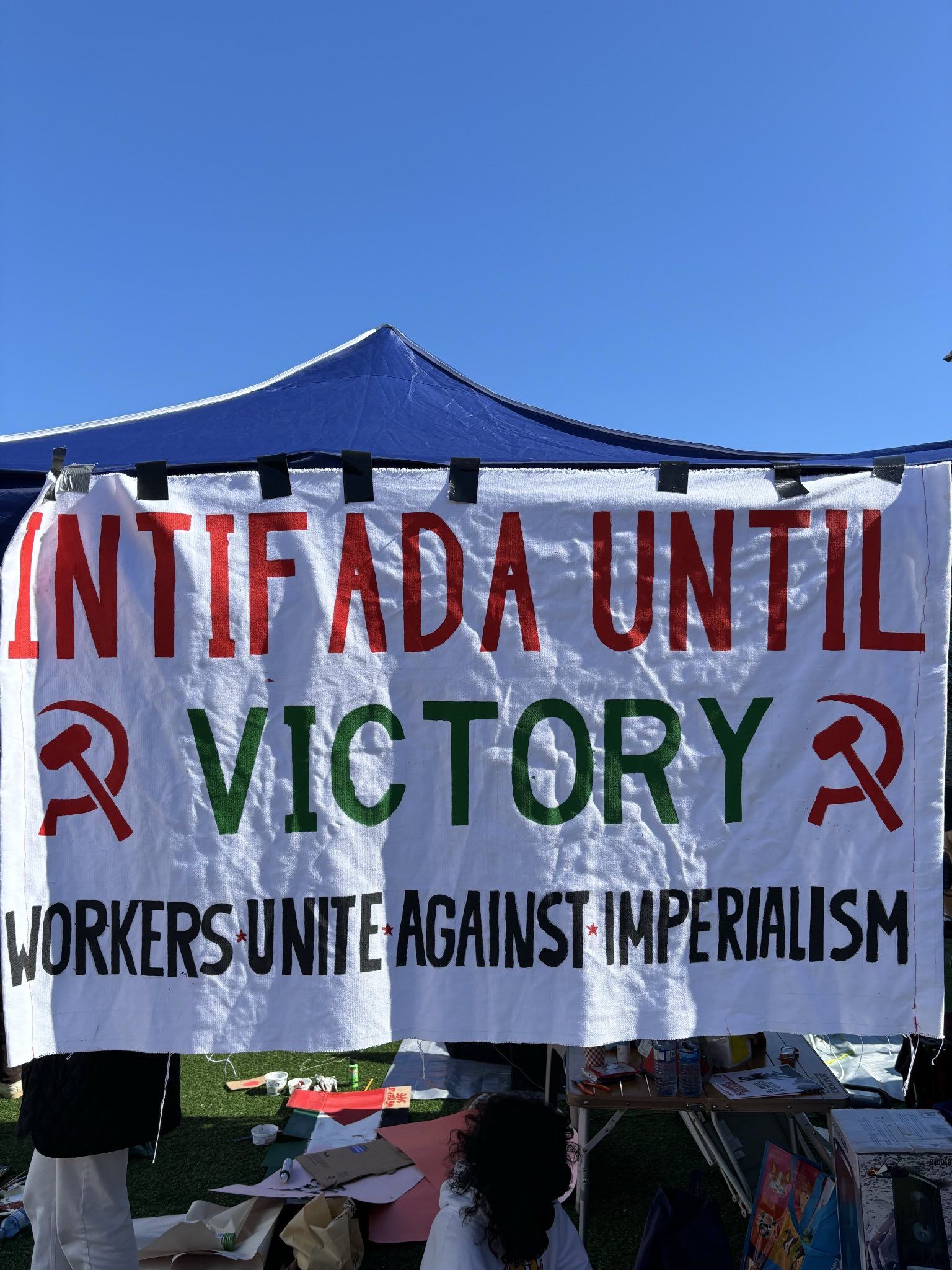 a sign by workers unite against imperialism displayed on a tent